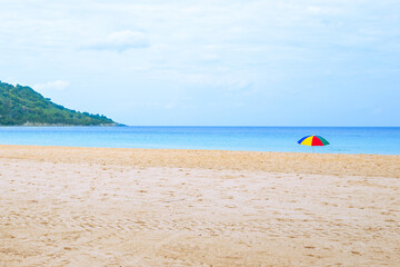 Empty sandy beach with bright umbrella and mountain. Travel and tourism