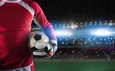 Goalkeeper holds the ball in the stadium during a football game
