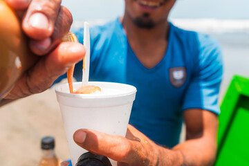 Close-up of a man spilling dulce de leche on shaved ice in Masachapa beach during the summer season in Nicaragua.Concept of self-employment in Latin America.