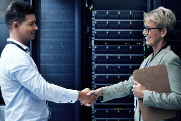 Always a pleasure programming with you. Shot of two technicians shaking hands while working together in a server room.