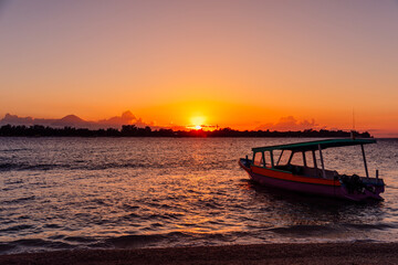 Sunset or sunrise at tropical beach with boat and ocean in Gili island