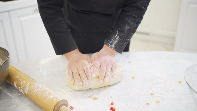 women kneads dough with candied fruits for easter cakes 
