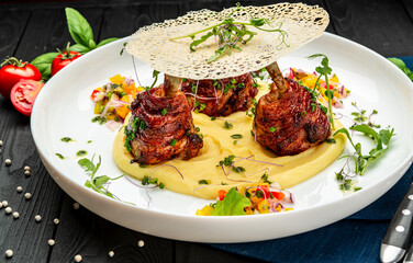 Chicken legs wrapped in bacon with barbecue sauce on mashed potatoes