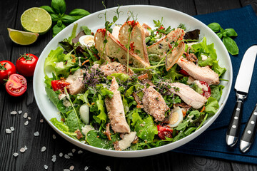 Fresh caesar salad in white plate on dark wooden table.