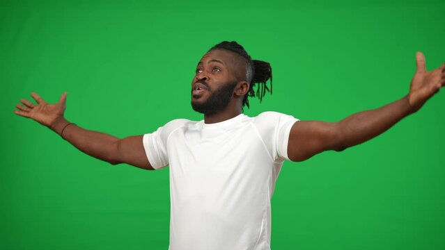 Portrait of inspired excited African American sportsman gesturing victory on green screen looking away. Happy successful footballer rejoicing goal at chromakey background mockup