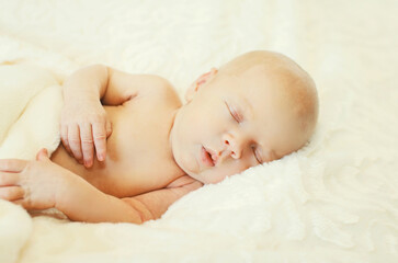 Close up portrait of infant sweet sleeping on white bed at home