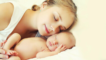 Portrait of sleeping mother and baby lying on the bed together at home