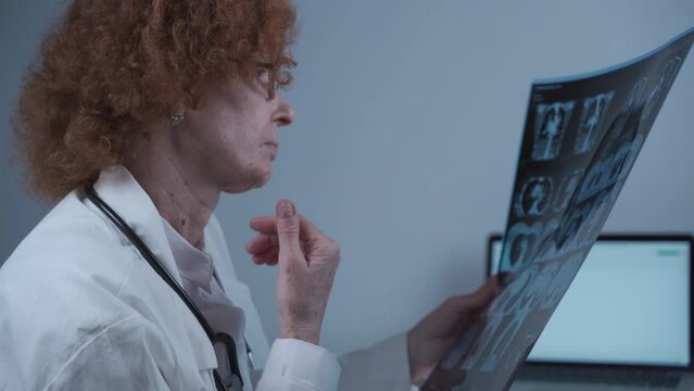 Mature caucasian woman doctor radiologist examining CT scan of patient's chest and lungs with Covid-19 in hospital office. Medical diagnosis concept. computed tomography of the lungs 