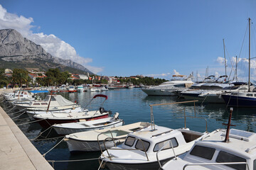 Fototapeta na wymiar Boats and yachts in the port of the resort town of Baska Voda on a sunny summer day, Dalmatia, Croatia