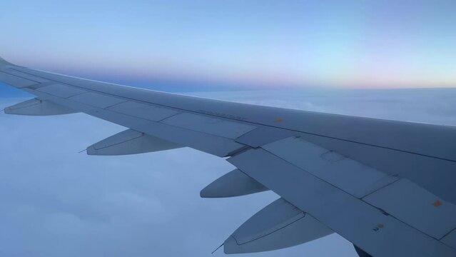 View from airplane window of horizon at blue sunset over clouds. Travel, air transportation concepts