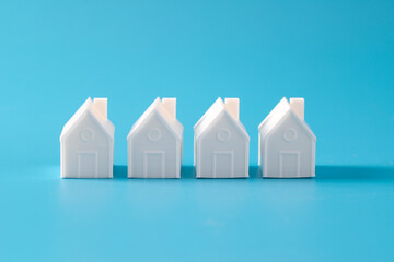 Miniature 3D printed model house on blue background for home or real estate market