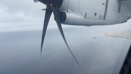 Jet engine airscrew view from airplane window with island and ocean below