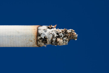 Burning cigarette. Macro photo. The cigarette ash is smoking. Blue background
