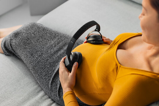 Pregnant Woman Holding Headphones On Belly Listening To Music For Unborn Baby Brain Development. Foetus Can Hear Through The Womb