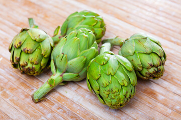 Obraz premium Fresh ripe artichokes lying on a wooden table