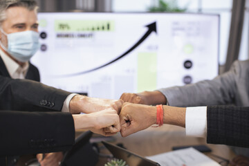 Close up of different ethnicity business people, putting fists together over workplace, celebrating successful startup, as symbol of responsibility and equal opportunities. Teamwork.