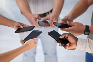 A connection that leads to success. Closeup shot of a group of businesspeople using their cellphones in synchronicity in an office.