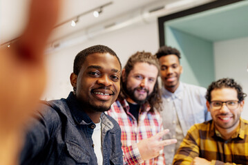 Obraz premium multiracial group of coworkers take a picture during a break from work at the office. friends taking a selfie