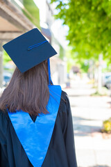 Young female school graduate on sidewalk.