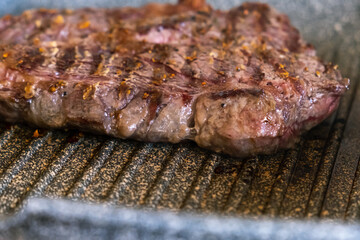 Juicy beef meat steak cooking on griddle pan at professional kitchen. Prime steak frying at grill. Delicious, modern cuisine