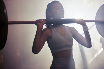 Witness her fitness. Shot of a sporty young woman getting ready to do a barbell overhead press in a gym.