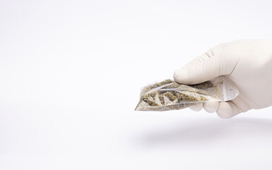 Hemp and drugs bag of marijuana in hands with gloves, white background.The concept of selling marijuana, hemp and drugs