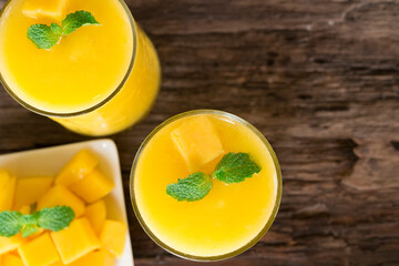 Mango smoothies orange colorful fruit juice beverage healthy high protein the taste yummy in glass on wood background from top view.
