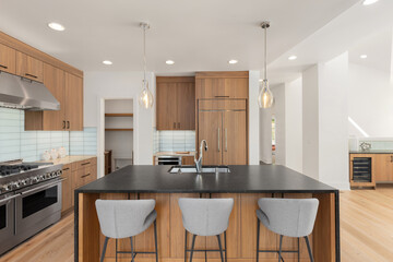 kitchen in new luxury home with waterfall island, stainless steel appliances, and pendant lights.
