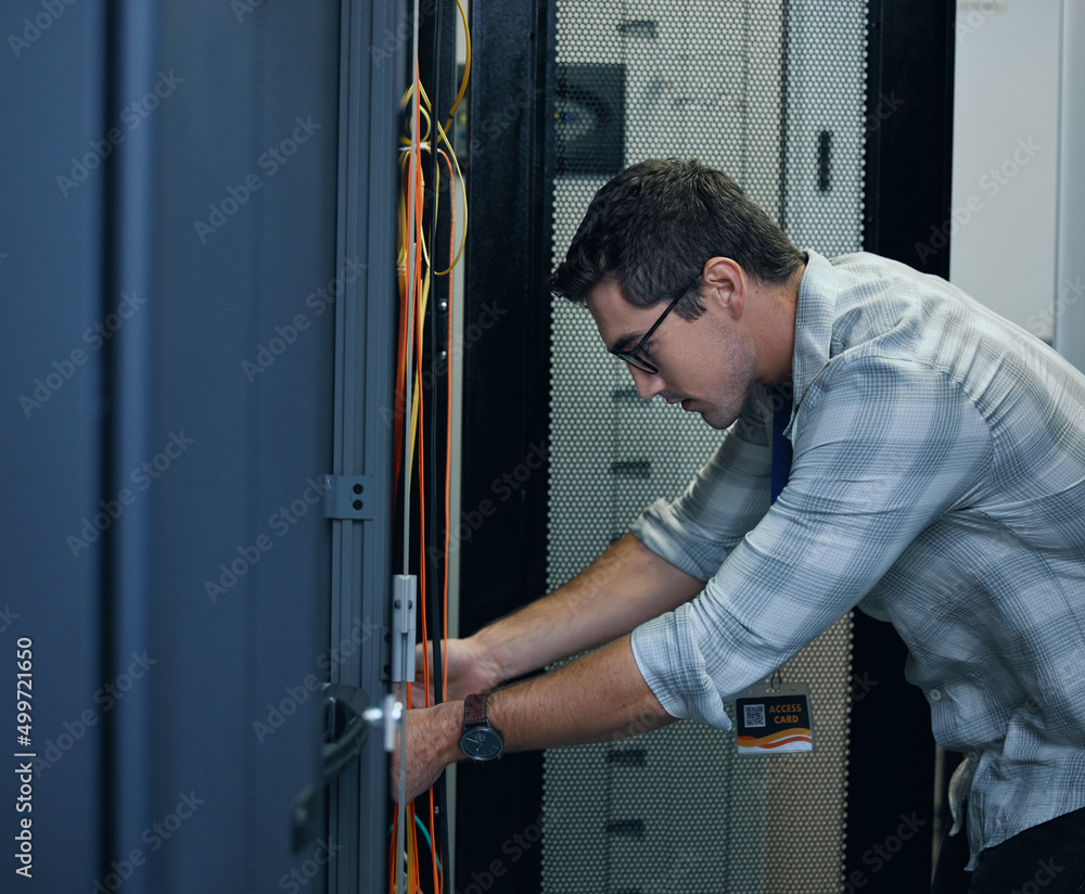 Poster hes the technician you need. cropped shot of a handsome young male programmer working in a server ro