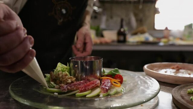 Gourmet. Food presentation. Cooking in the kitchen. Male chef decorating spider crab dish with a pipping bag.