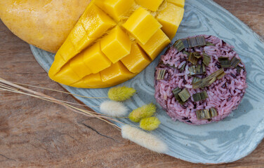 Close-up of Fresh ripe yellow mango fruit (Barracuda mango) and Riceberry topping pandan leaf on...