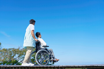 介護士と車椅子に乗った高齢者　屋外