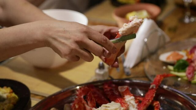 People eating at the restaurant. closeup view of female caucasian hands eating spider crab legs. 