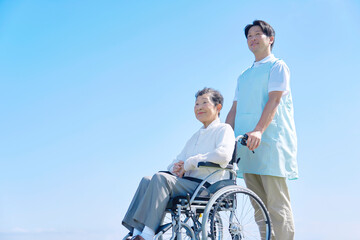 介護士と車椅子に乗った高齢者　屋外