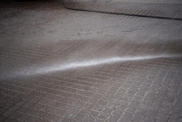 dustman cleaning street with water
