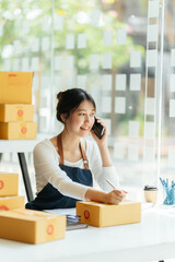 Successful Asian women entrepreneur with parcel boxes in her own job shopping online business at home office. start up small business, sme concept.