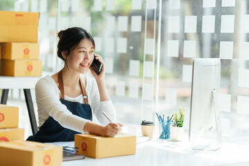 Successful Asian women entrepreneur with parcel boxes in her own job shopping online business at home office. start up small business, sme concept.
