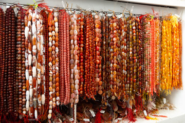 Multicolored beads made of gems strung on thread displayed on stand in store of jewelry accessories