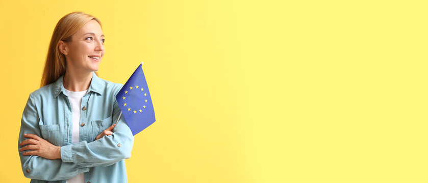 Mature woman holding flag of European Union on yellow background with space for text