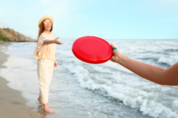 Happy young women playing frisbee on sea beach
