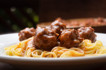 Almondegas com macarrão, pasta, spaghetti com molho de tomate em um prato branco e um fundo escuro...