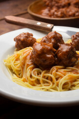 Almondegas com macarrão, pasta, spaghetti com molho de tomate em um prato branco e um fundo escuro...