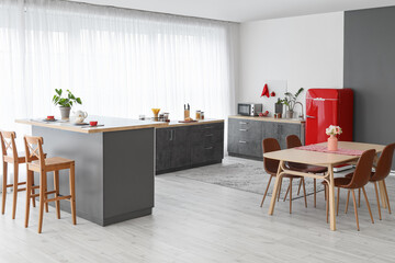 Interior of modern kitchen with red fridge, counters and dining table