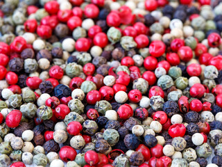 Black, red, green, white dried peppercorns background or texture. Heap of spice. Mix of four different peppers. Selective focus. Food backgrond, full frame, close up, copy space