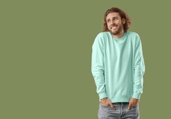 Smiling young man in sweatshirt on green background