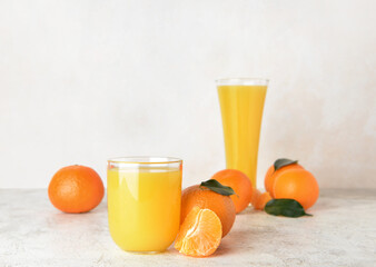 Glasses of delicious tangerine juice on light background