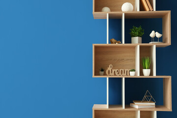 Wooden shelving unit with books and decor near blue wall
