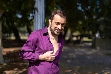 Portrait of a mature bearded man leaning on a lamp post looking at the camera