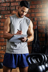 Fully equipped gym, happy clients. Shot of a young man doing inventory while working in a gym.