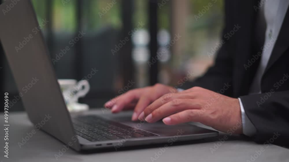 Poster Close-up of green notebook computer screen with the fingers of a man in a business suit typing on a keyboard